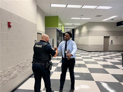 Principal fist bumping and SRO at James Clemens High School in hall